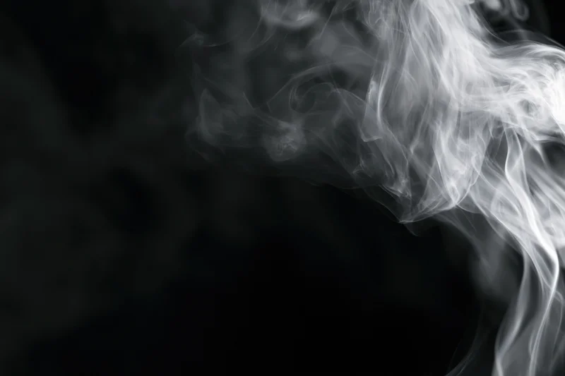 Wispy white smoke swirling upward against a black background