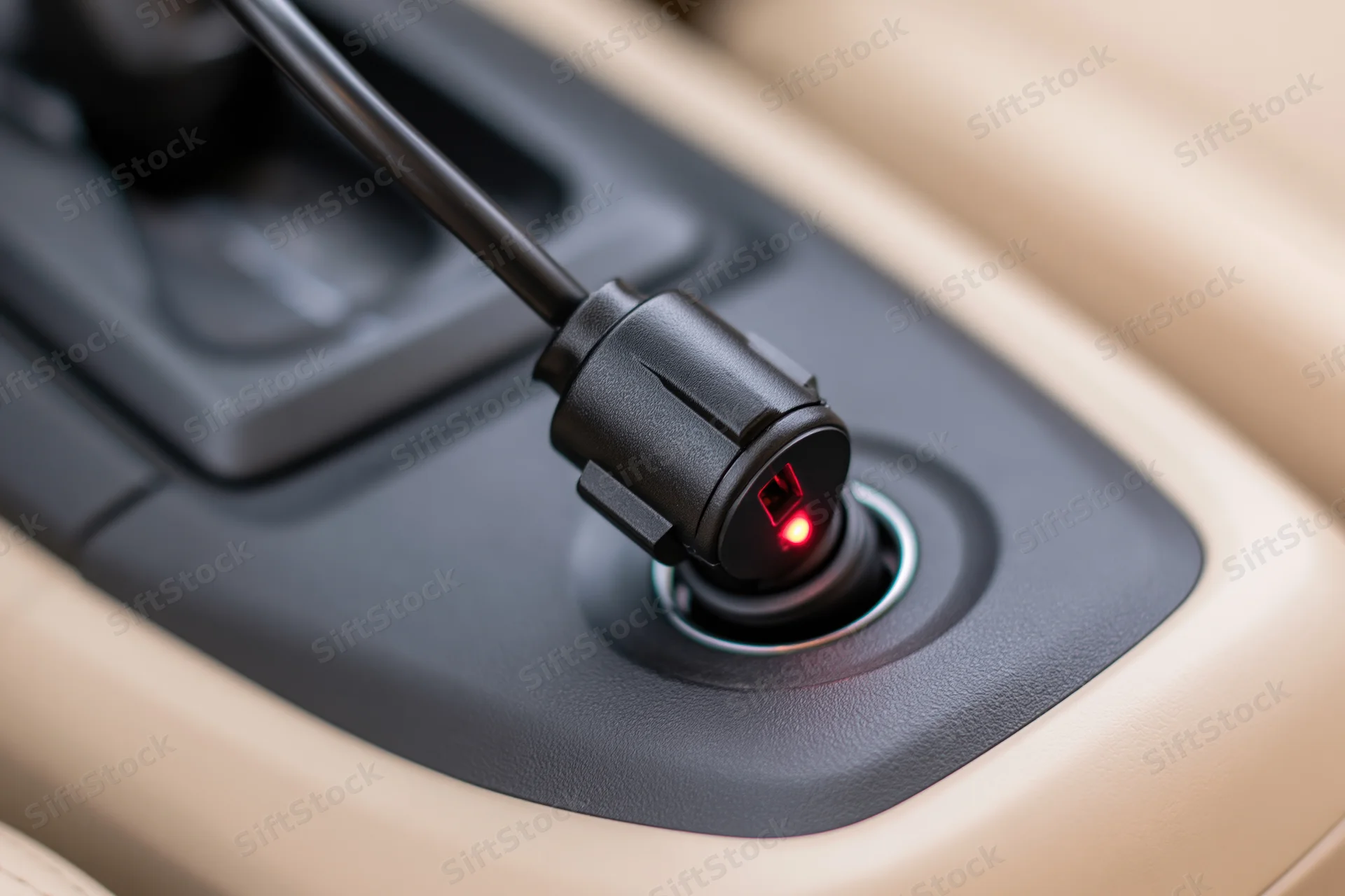 Black car charger adapter plugged into cigarette lighter socket in vehicle console