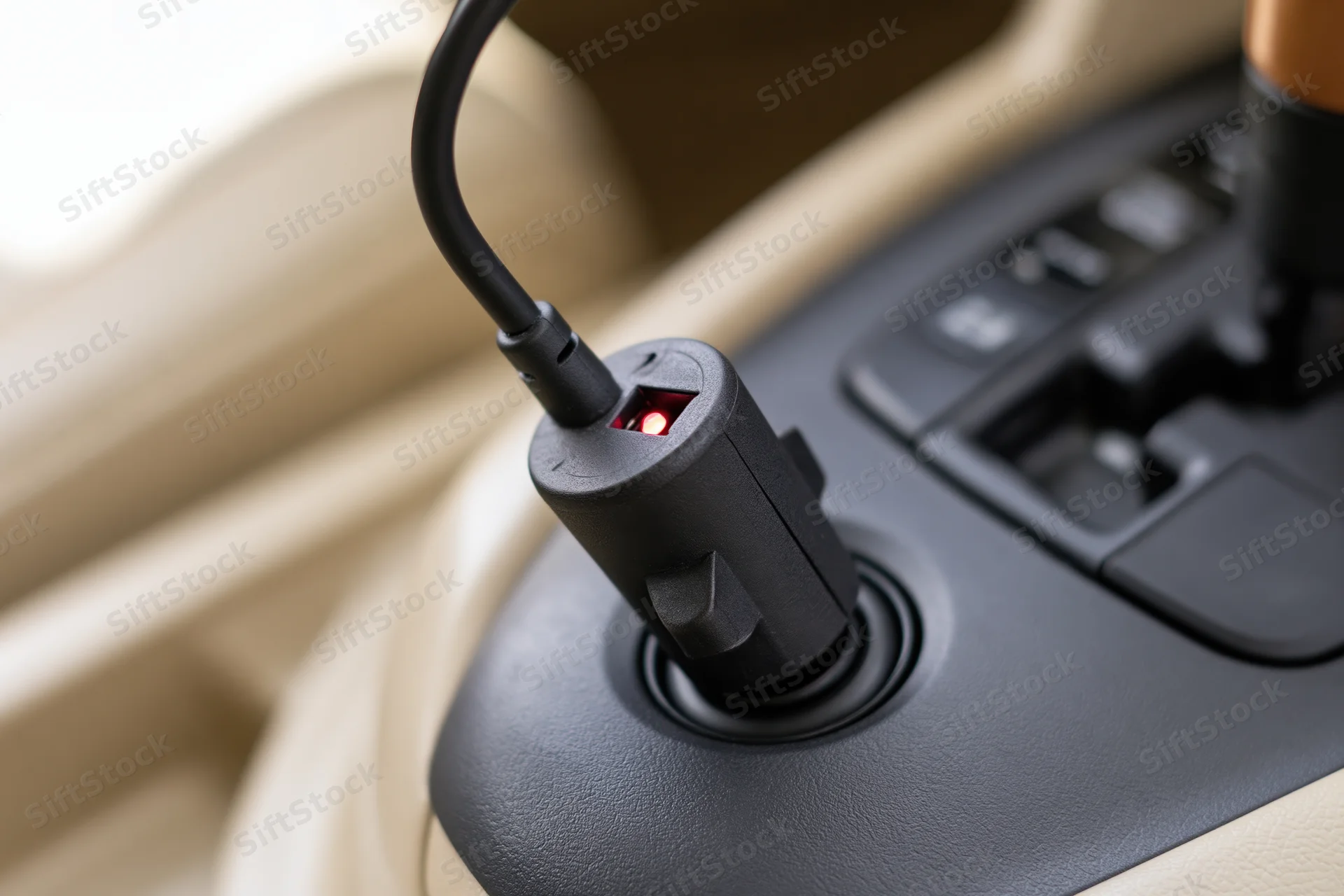 Black car charger adapter plugged into cigarette lighter socket in vehicle interior