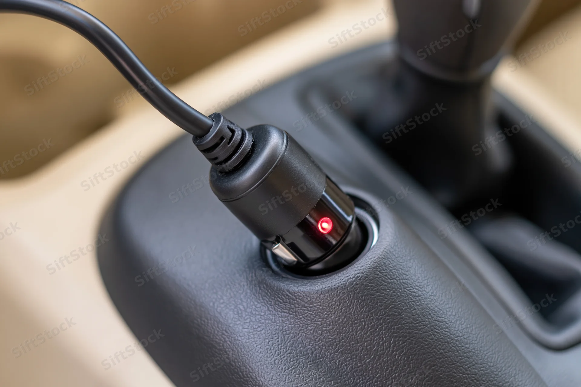 Black car charger adapter plugged into cigarette lighter socket in vehicle console
