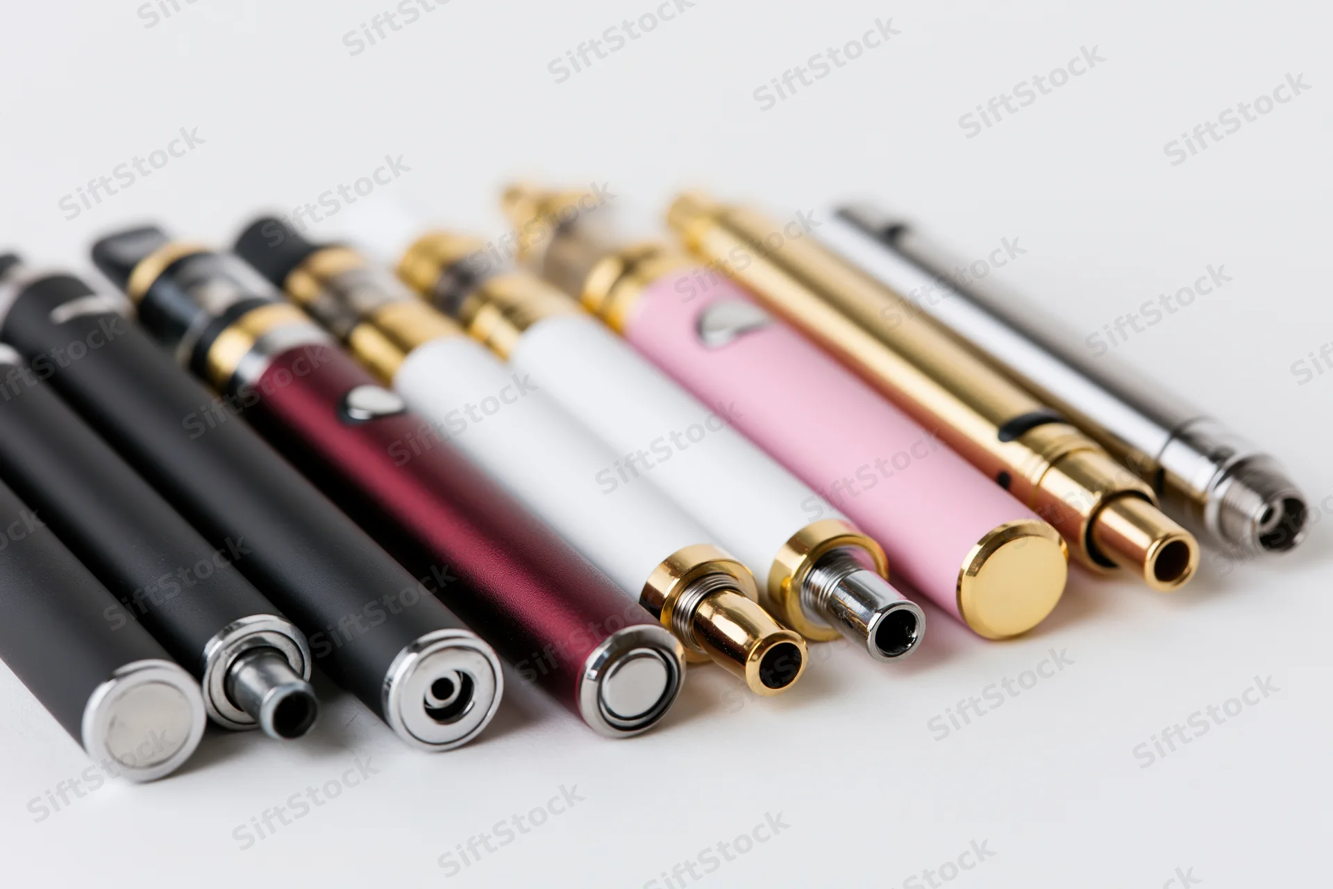 Collection of colorful vape pens arranged in a row on a white surface