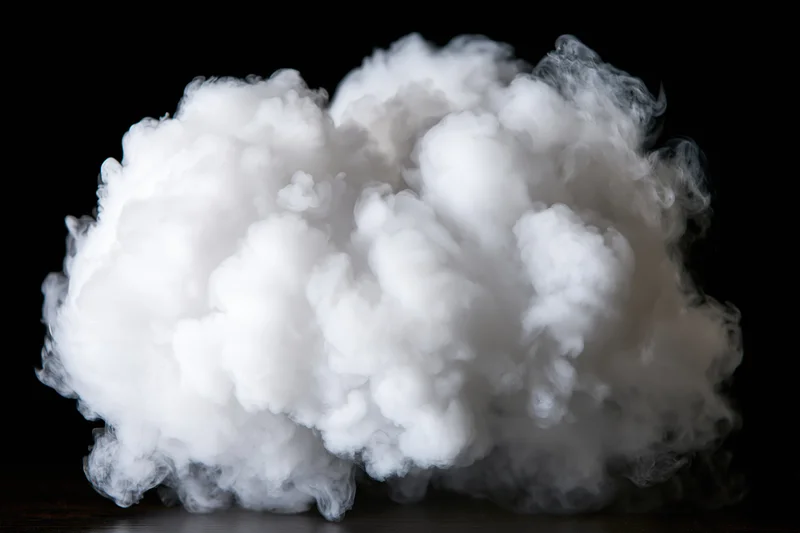 Dense white smoke cloud billowing mid-air against black background