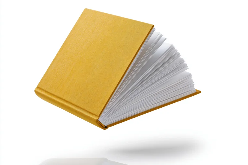 Open hardcover book with mustard-yellow cloth cover floating against white background