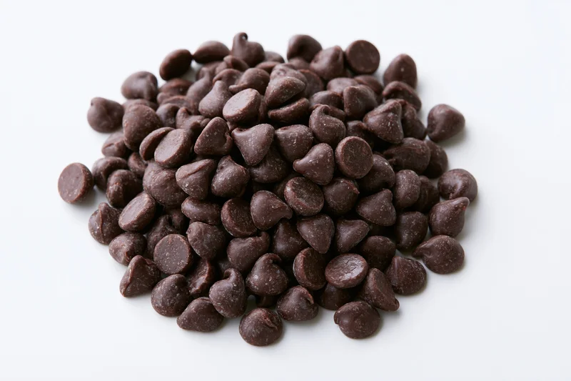 Loose pile of dark chocolate chips on white background