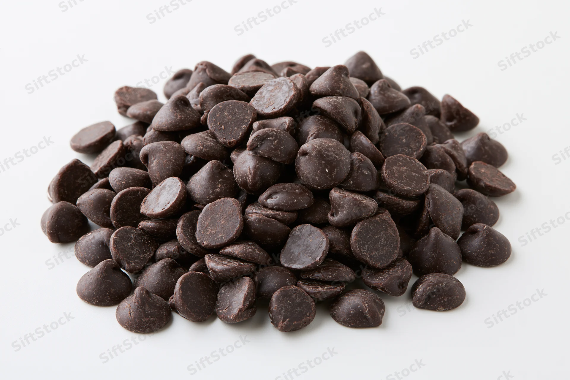 A pile of dark chocolate chips heaped on a white background