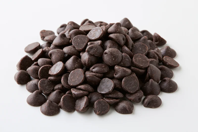 A pile of dark chocolate chips heaped on a white background