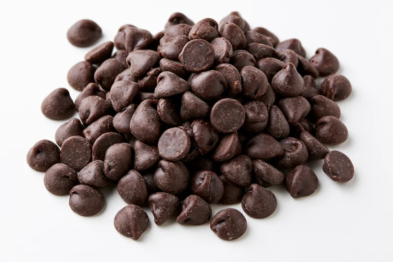 Pile of dark chocolate chips on white background