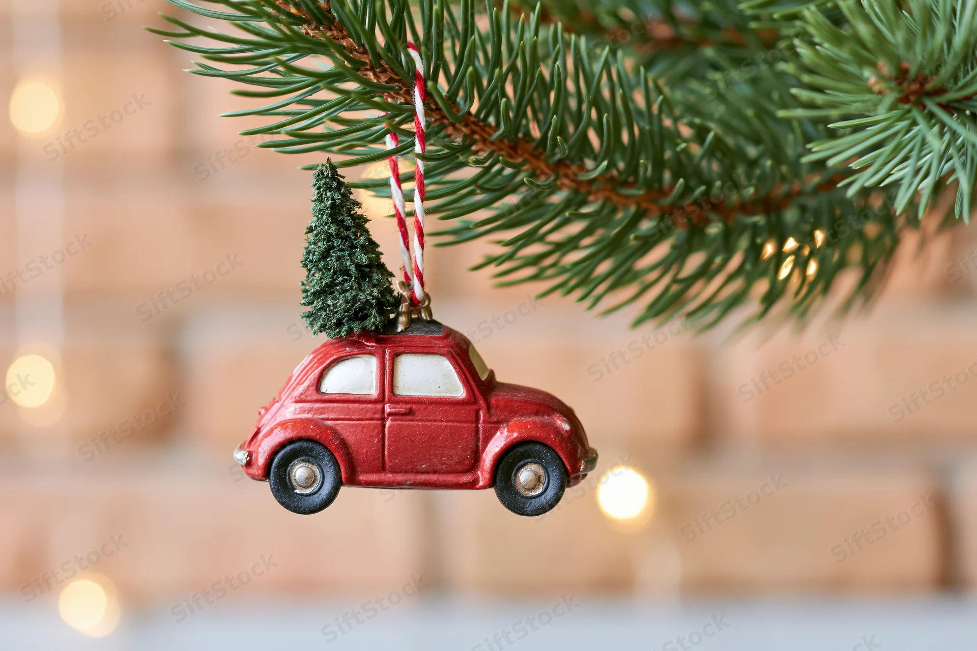 Red vintage car ornament with miniature tree on roof hanging from christmas tree branch