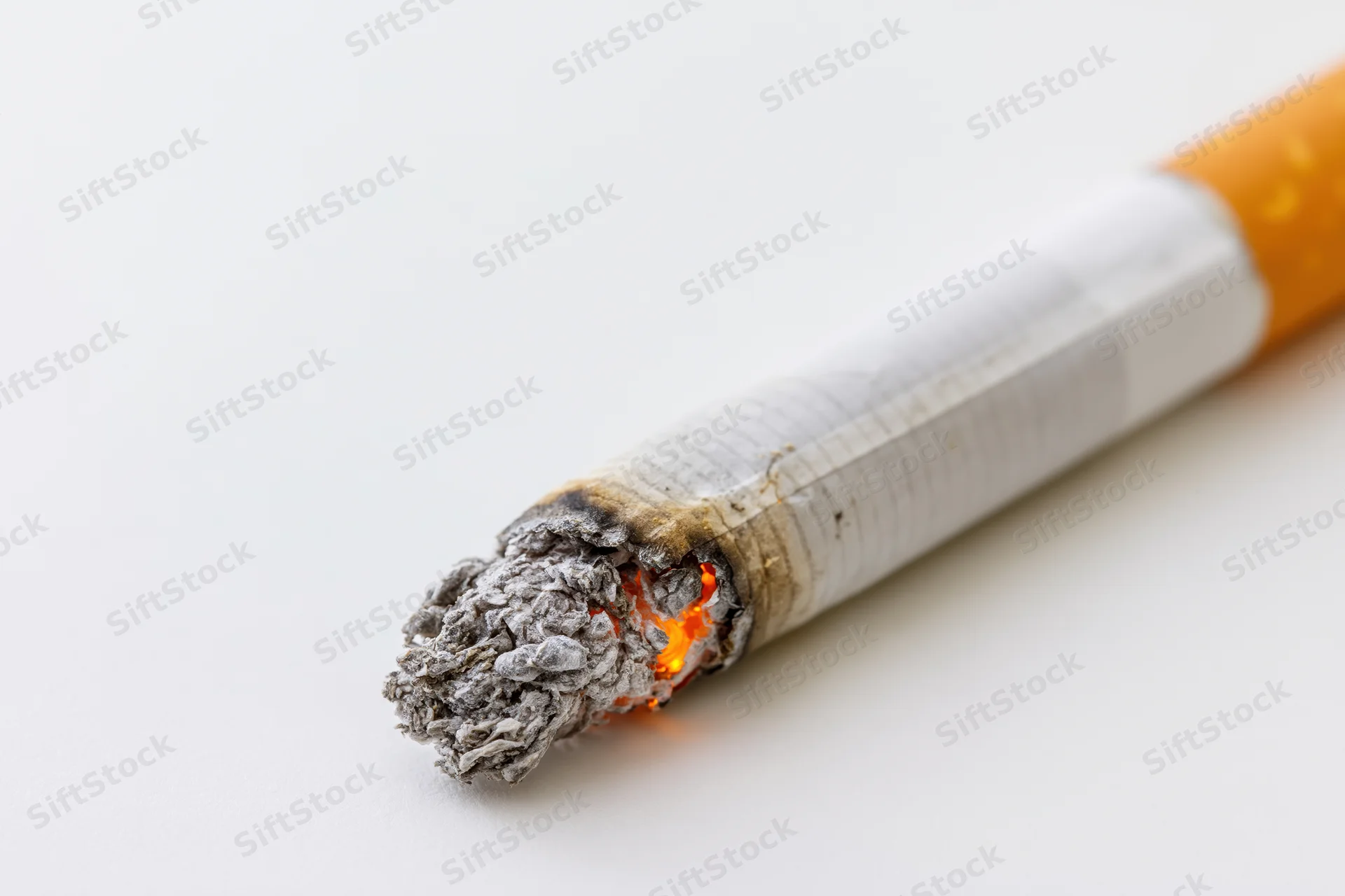 Lit cigarette angled diagonally with burning tip and ash on white background