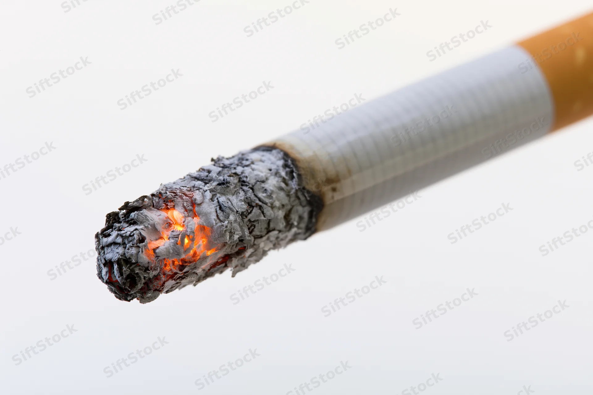 Lit cigarette angled diagonally with glowing ember and ash against white background