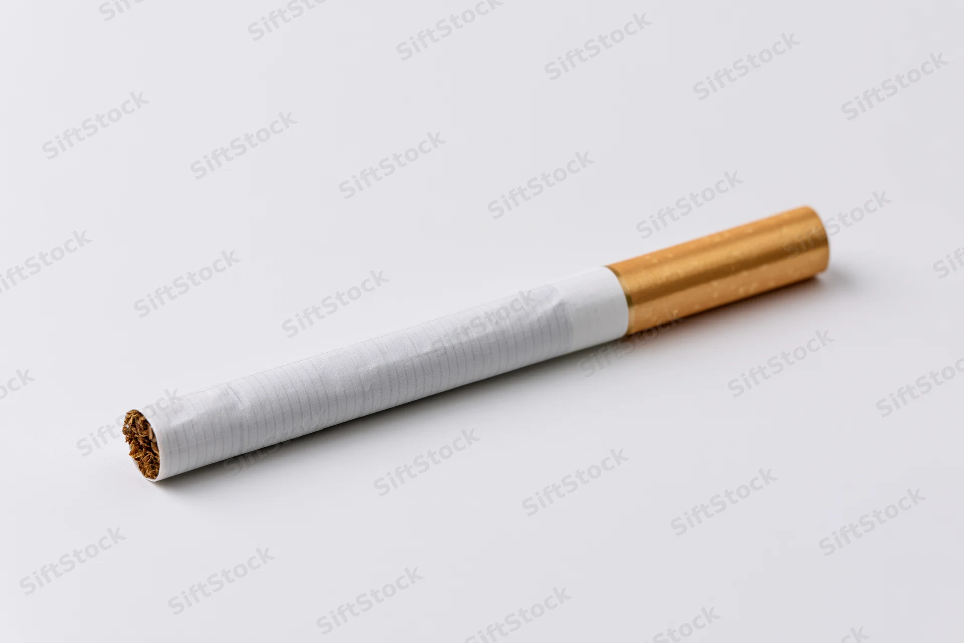 Unlit cigarette lying diagonally on white background with visible tobacco and filter