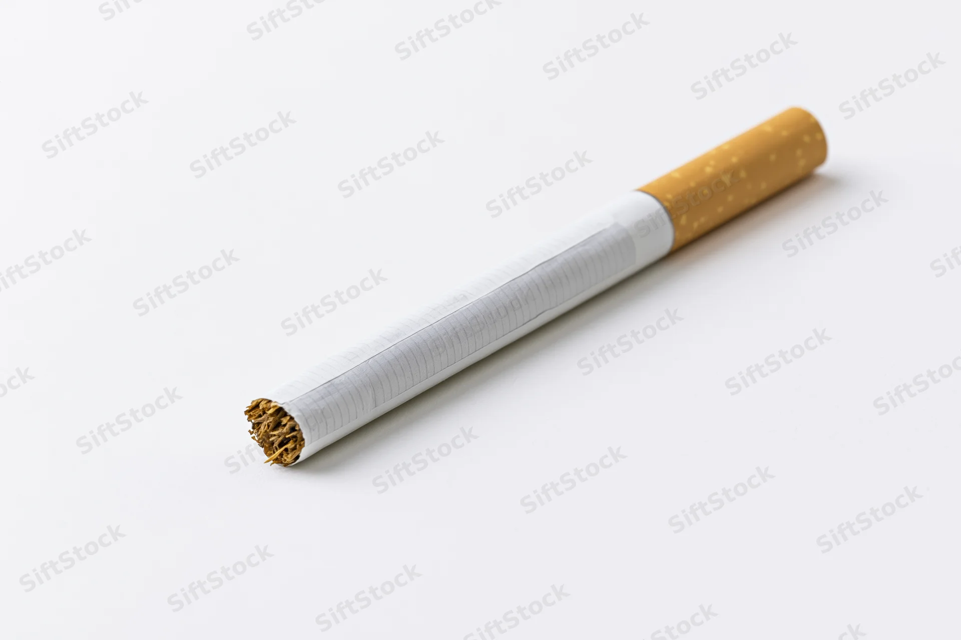 Unlit cigarette lying diagonally on white background