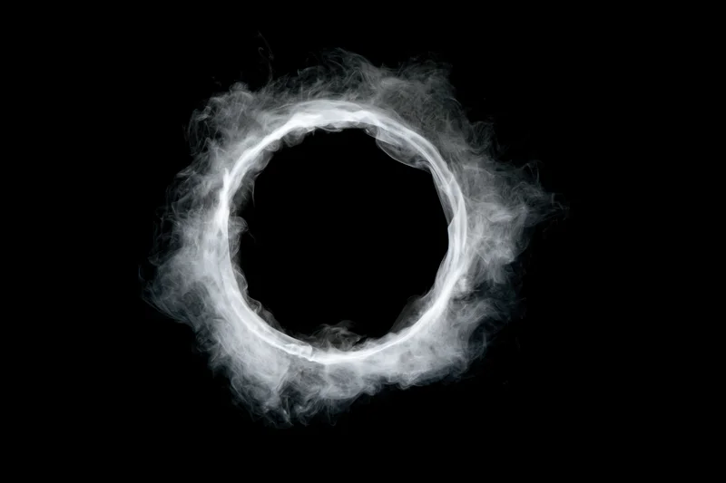White smoke ring floating in midair against black background
