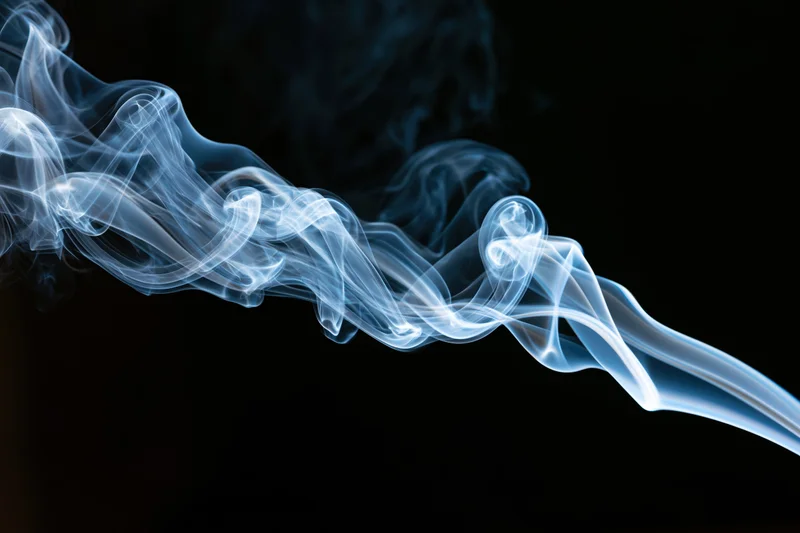 A wisp of white and blue smoke curling and twisting horizontally across a black background