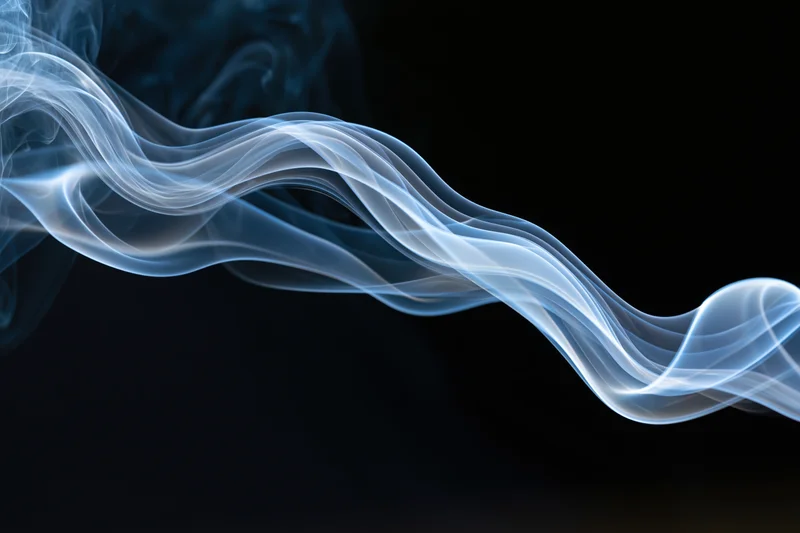 A wisp of white and blue smoke curling and twisting horizontally across a dark background