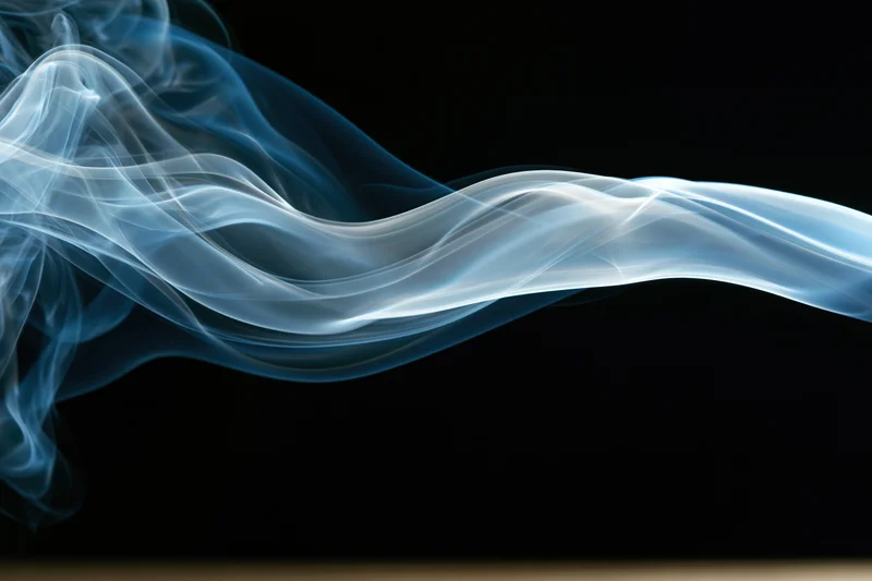 A wisp of white and blue smoke swirling horizontally against a black background