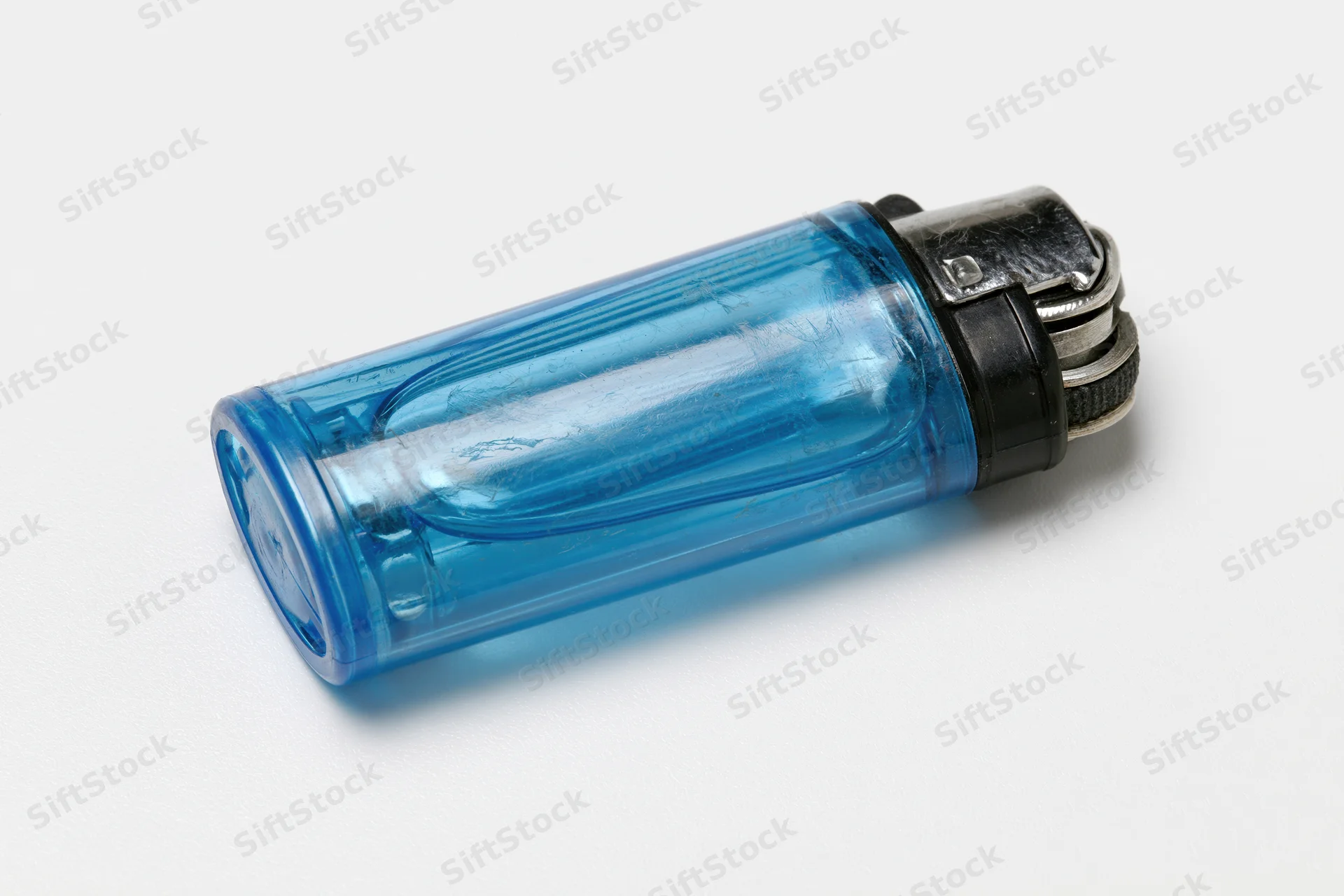 Translucent blue plastic disposable lighter lying on white surface