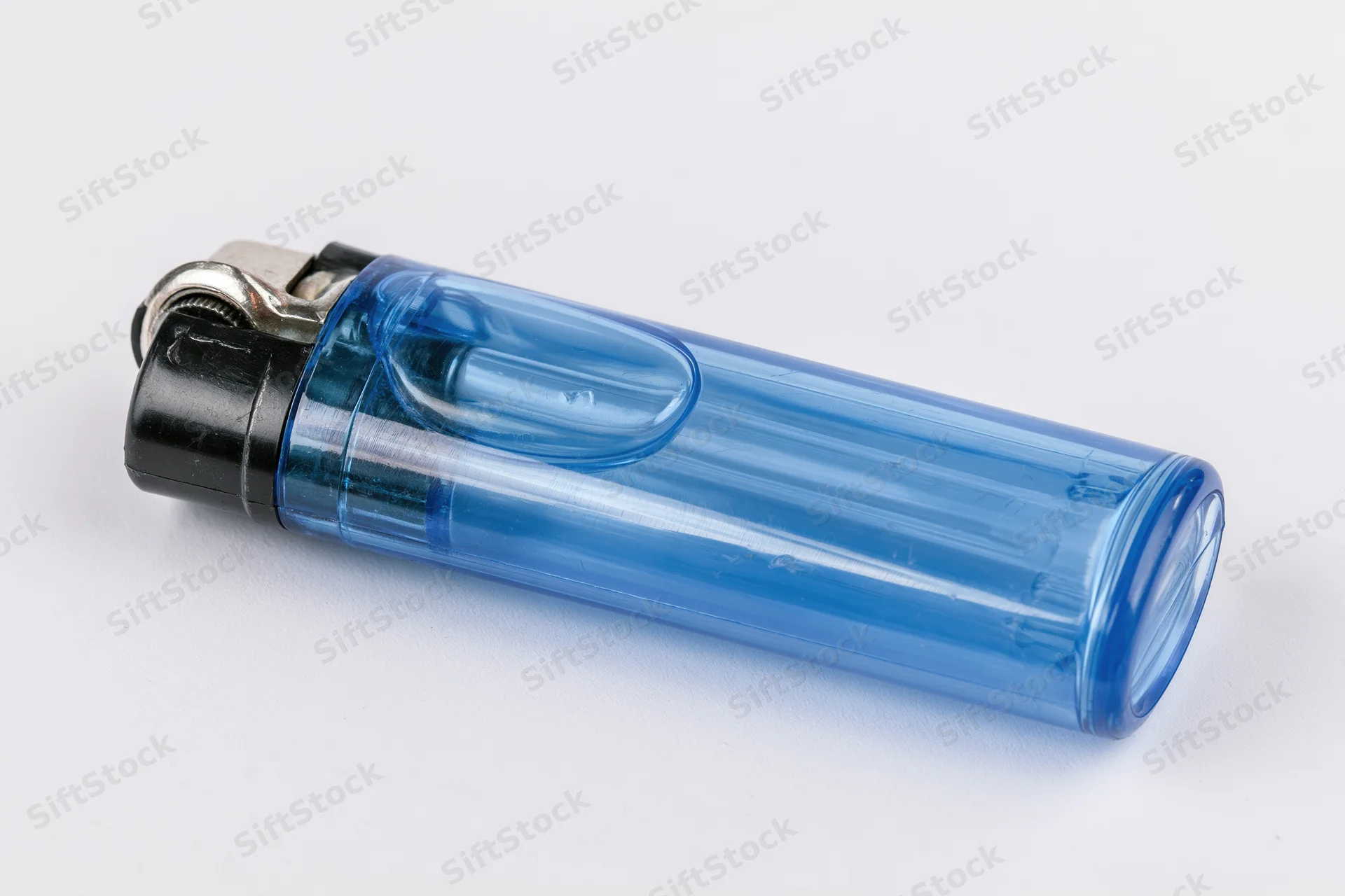 Translucent blue plastic disposable lighter lying on white surface