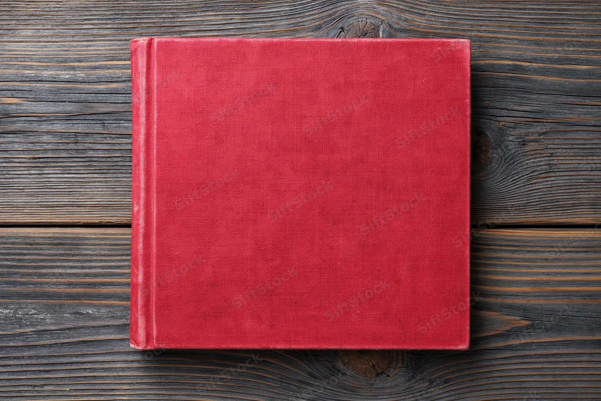 Red hardcover book lying flat on rustic wooden surface