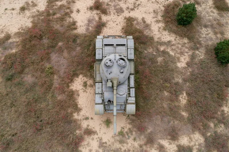 Aerial top-down view of a gray military tank on arid desert terrain with sparse vegetation