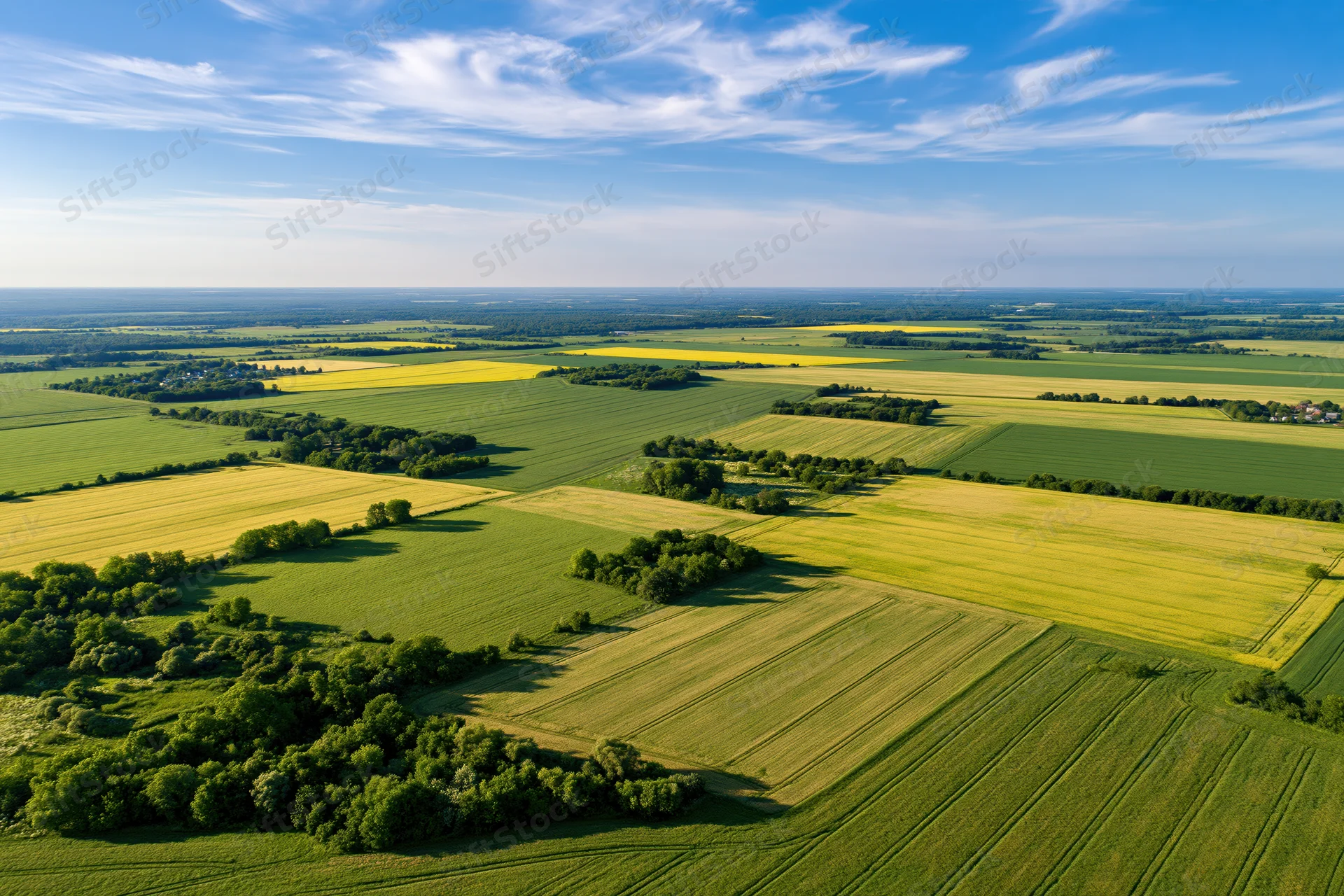 Aerial view of patchwork farmland with green and yellow crops under a blue sky