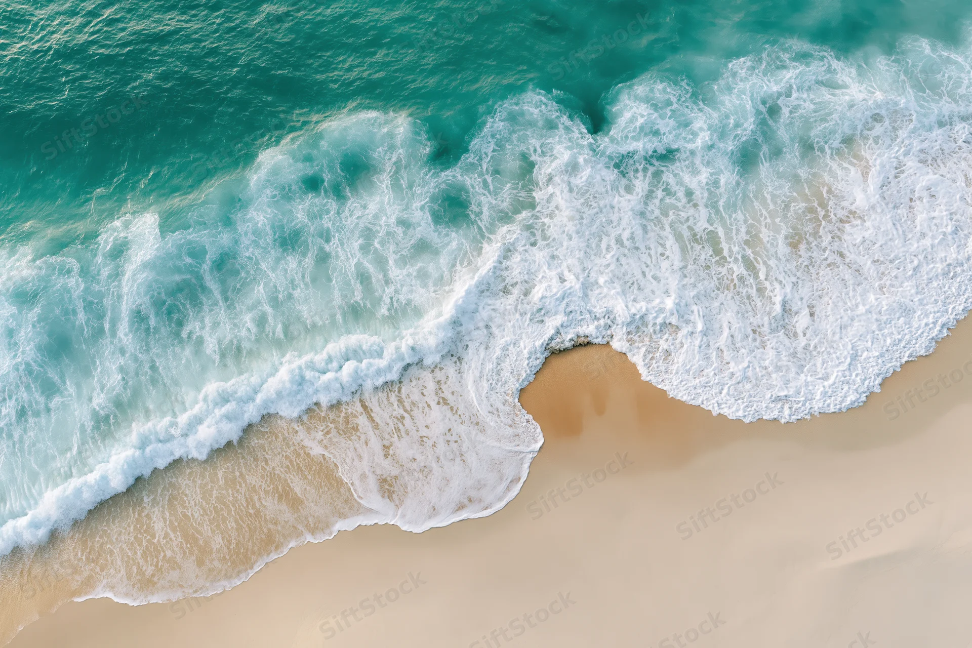 Aerial view of turquoise ocean waves crashing onto sandy beach