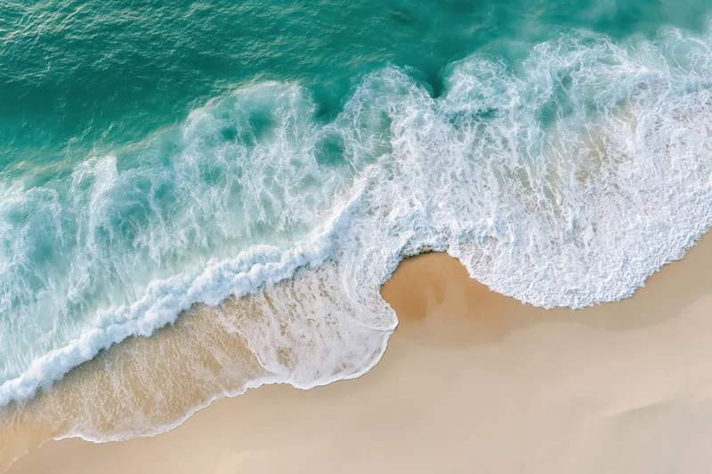 Aerial view of turquoise ocean waves crashing onto sandy beach