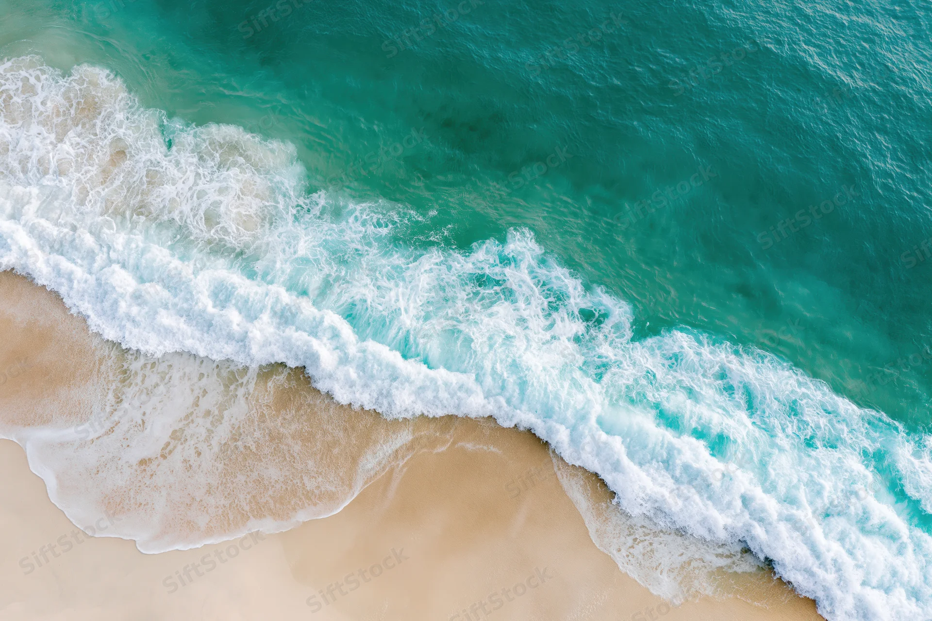 Aerial view of turquoise ocean waves breaking on a sandy tropical beach