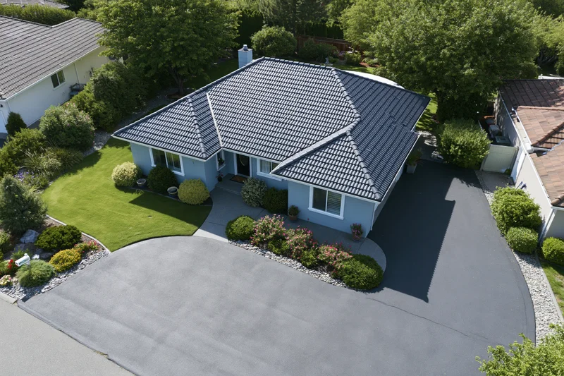 Aerial drone view of a light blue single-story suburban house with tiled roof and landscaped yard