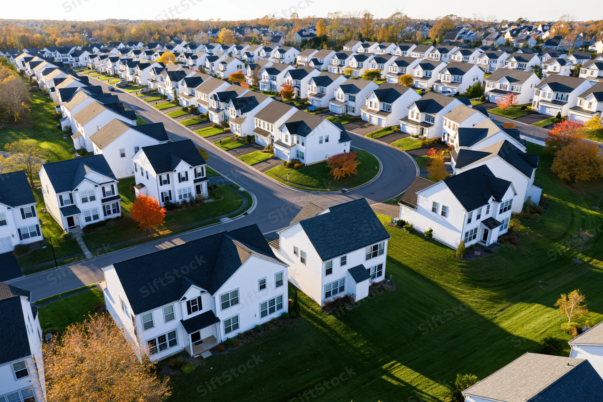 Aerial view of suburban neighborhood with white houses and autumn trees