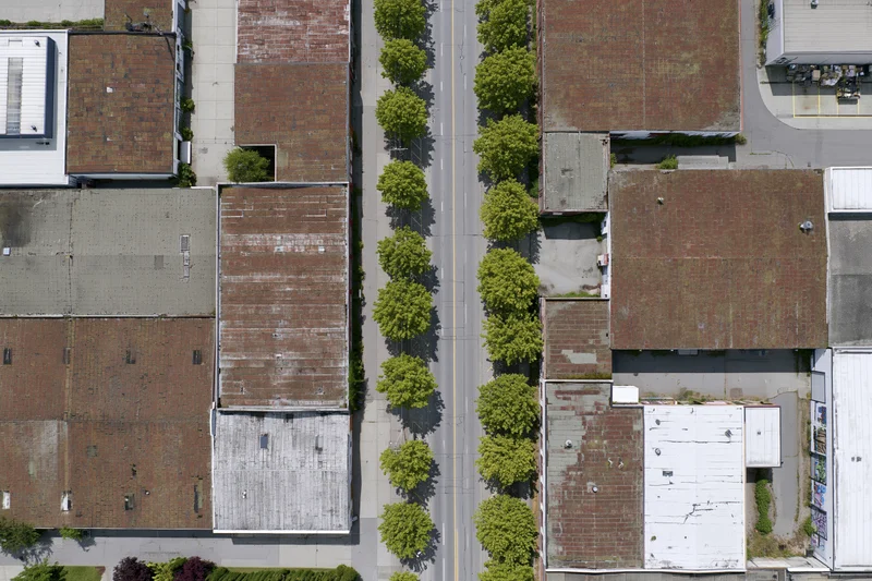 Aerial top-down view of aging industrial district with brick buildings and tree-lined street