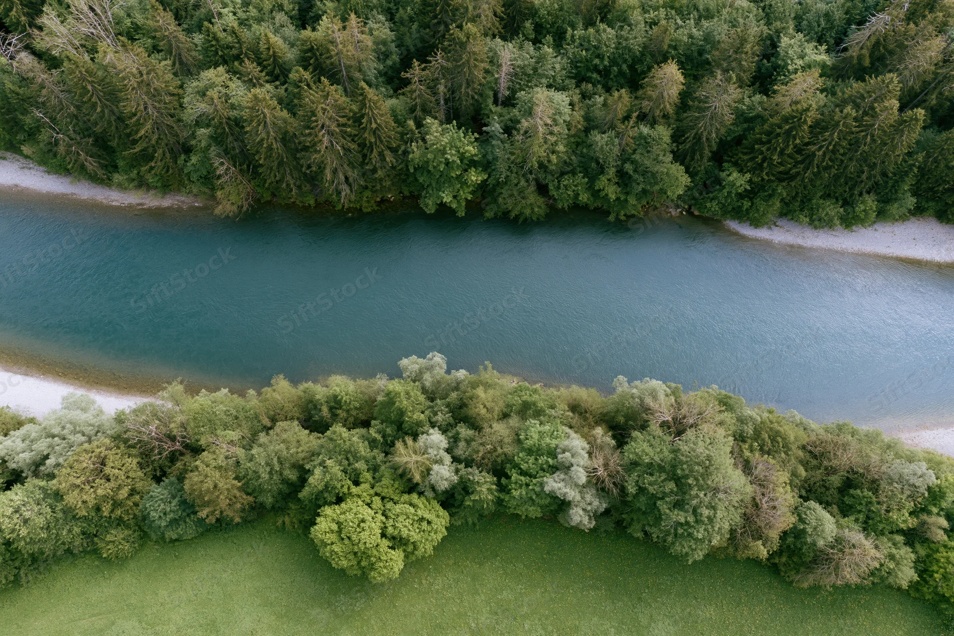 Aerial top-down view of a calm river flowing horizontally through a forested landscape