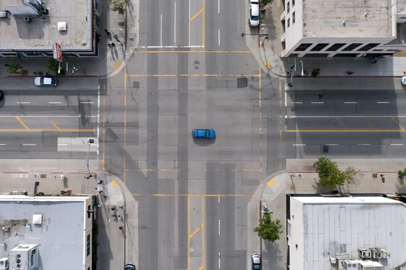 Aerial top-down view of an urban four-way street intersection with vehicles and buildings