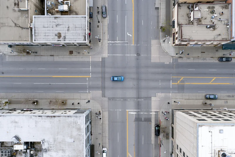 Aerial top-down view of an urban four-way street intersection with vehicles and surrounding buildings