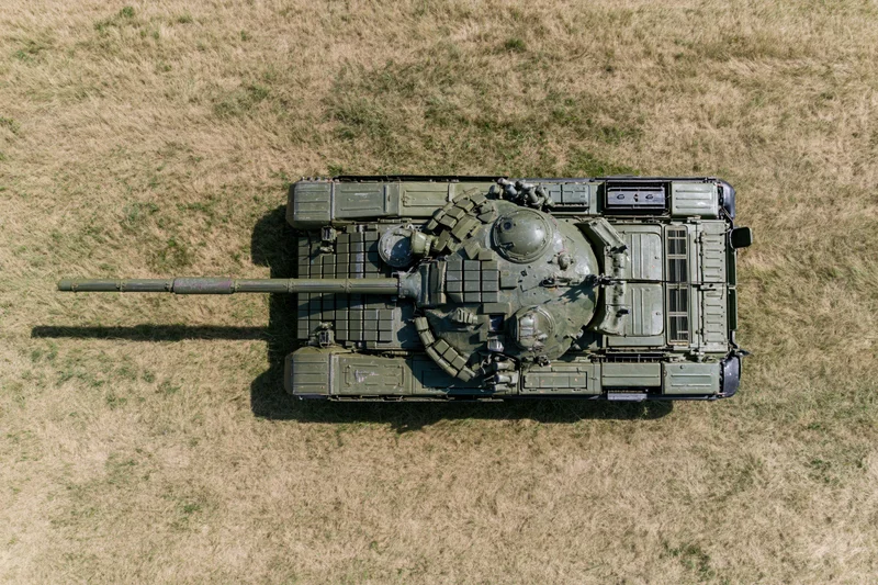 Aerial top-down view of a soviet-era main battle tank parked on dry grass field