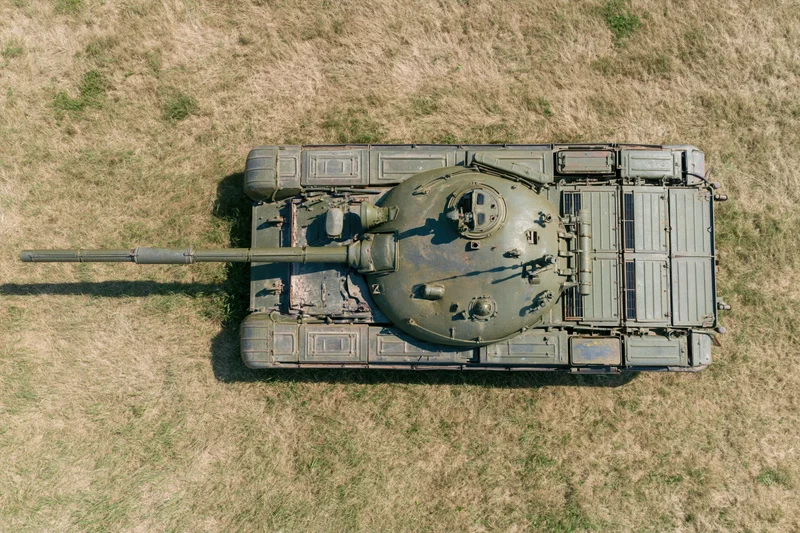 Aerial top-down view of a soviet-era main battle tank parked on dry grass field