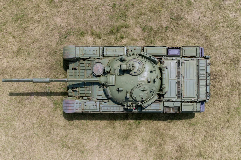 Aerial top-down view of a soviet-era main battle tank parked on dry grass field