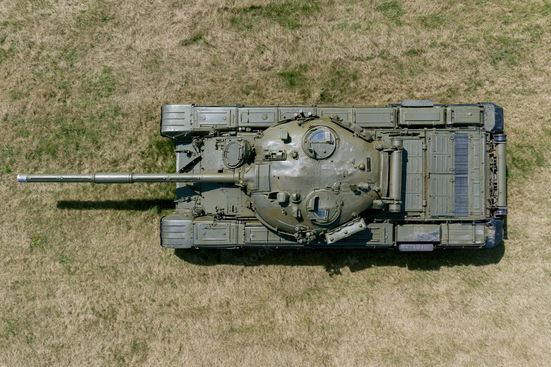 Aerial top-down view of a soviet-era main battle tank parked on dry grass field