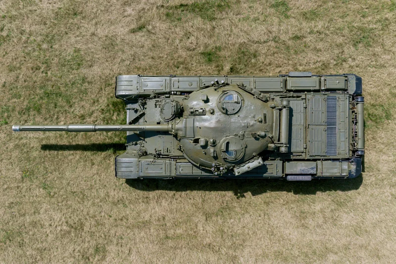 Aerial top-down view of a soviet-era main battle tank parked on dry grass field