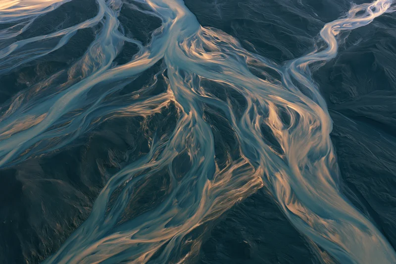 Aerial top-down view of a braided glacial river delta flowing across icy terrain in Iceland