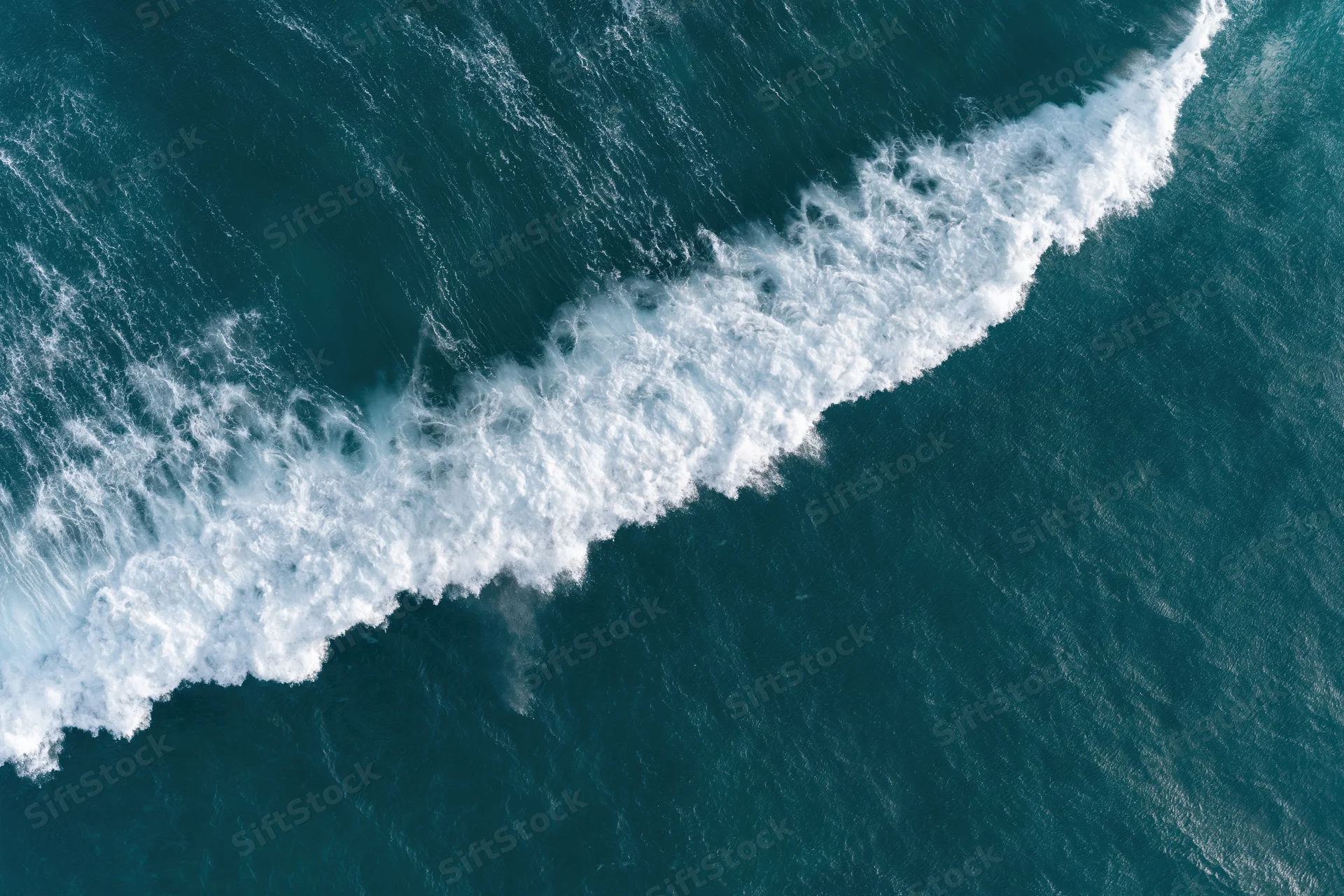 Aerial top-down view of a breaking ocean wave with white foam and churning water