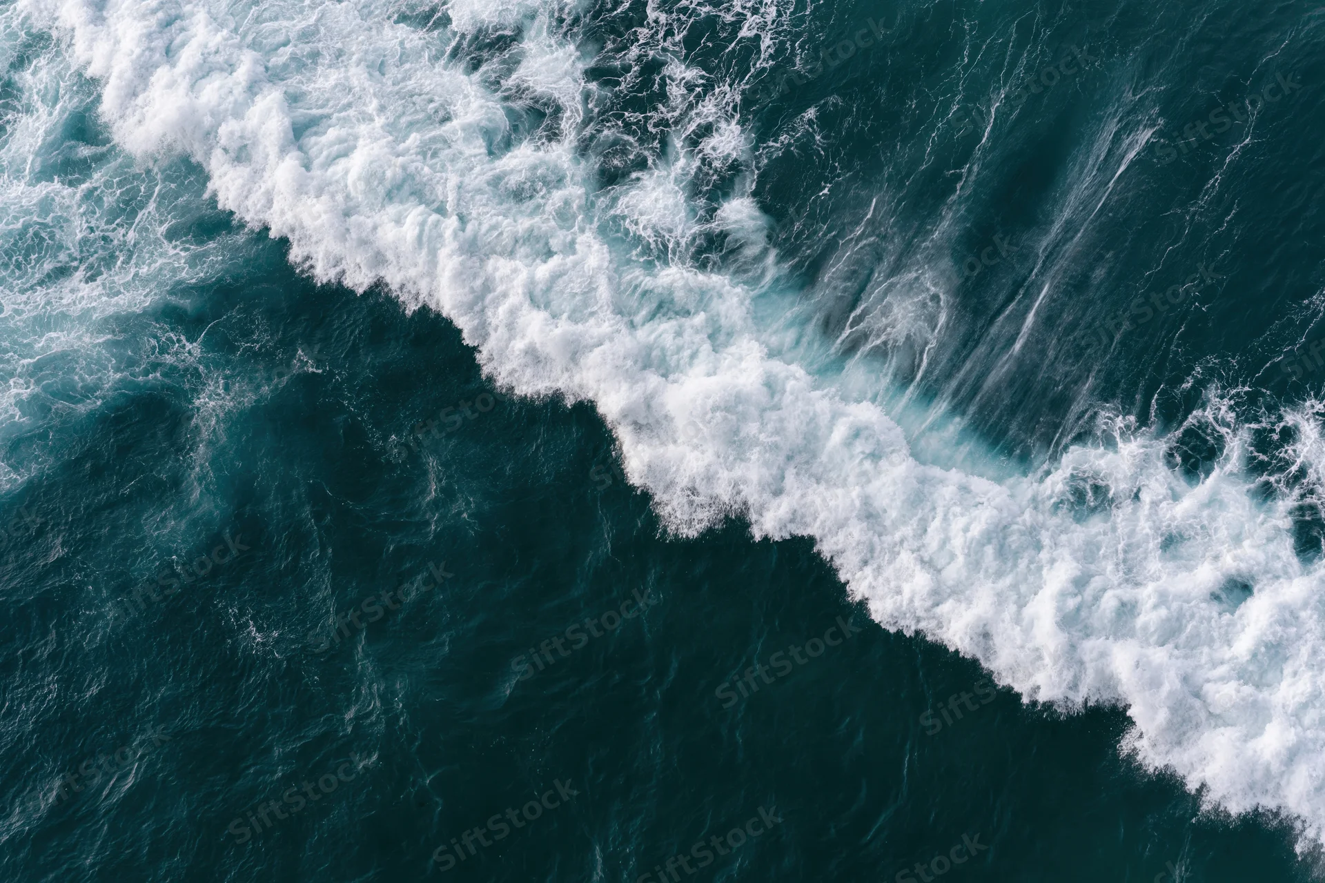 Aerial top-down view of a breaking ocean wave with white foam and churning water