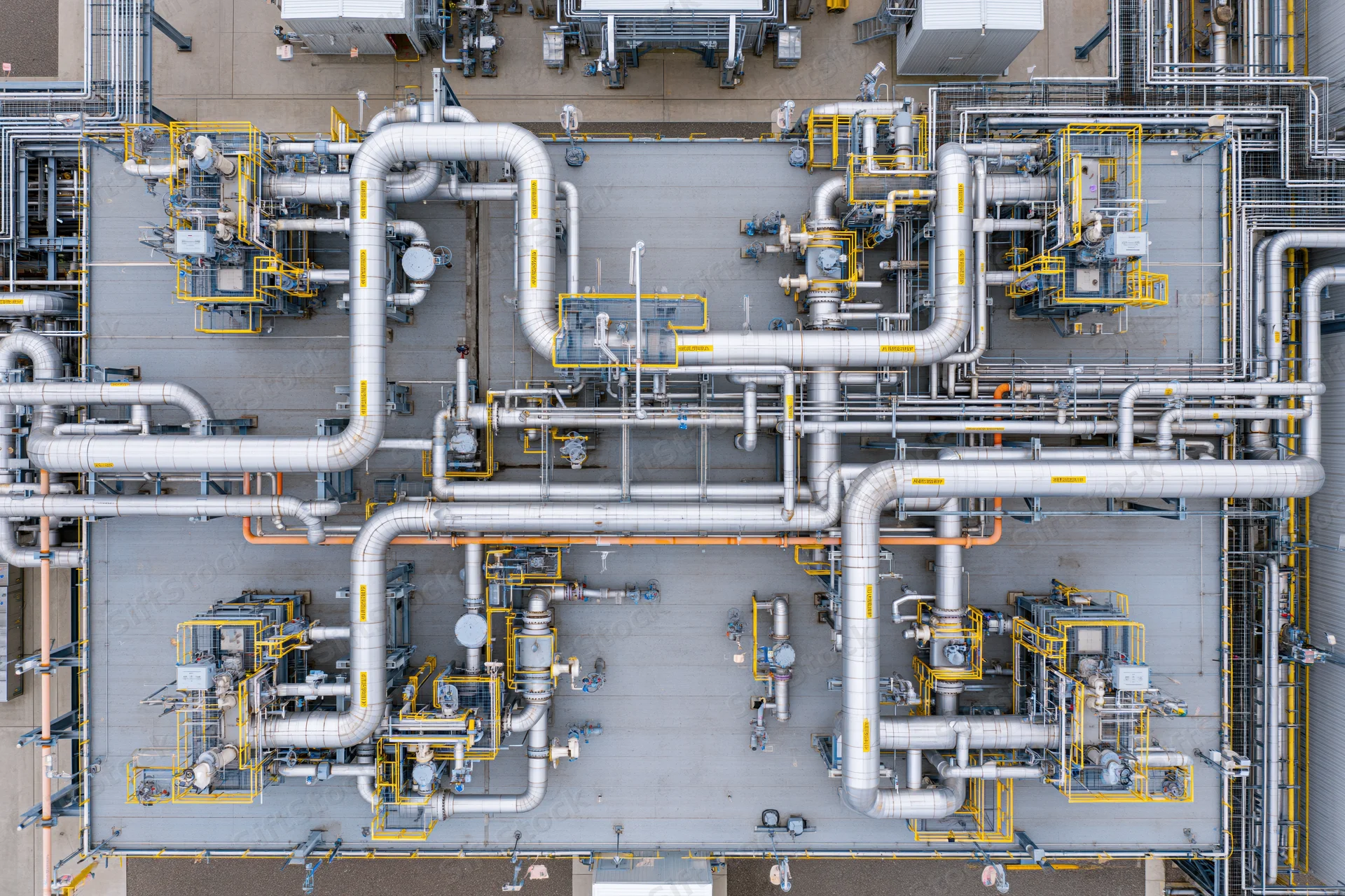Aerial top-down view of industrial power plant rooftop with network of pipes and machinery