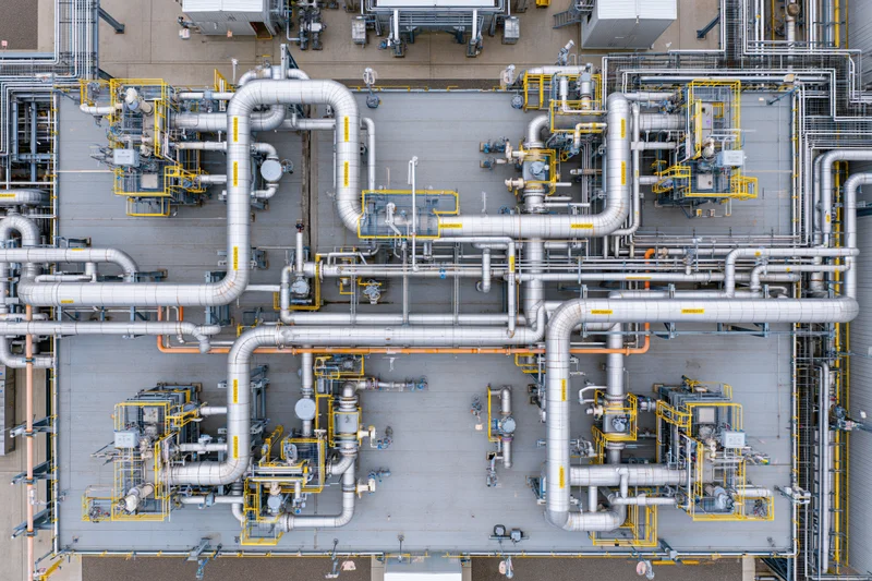 Aerial top-down view of industrial power plant rooftop with network of pipes and machinery