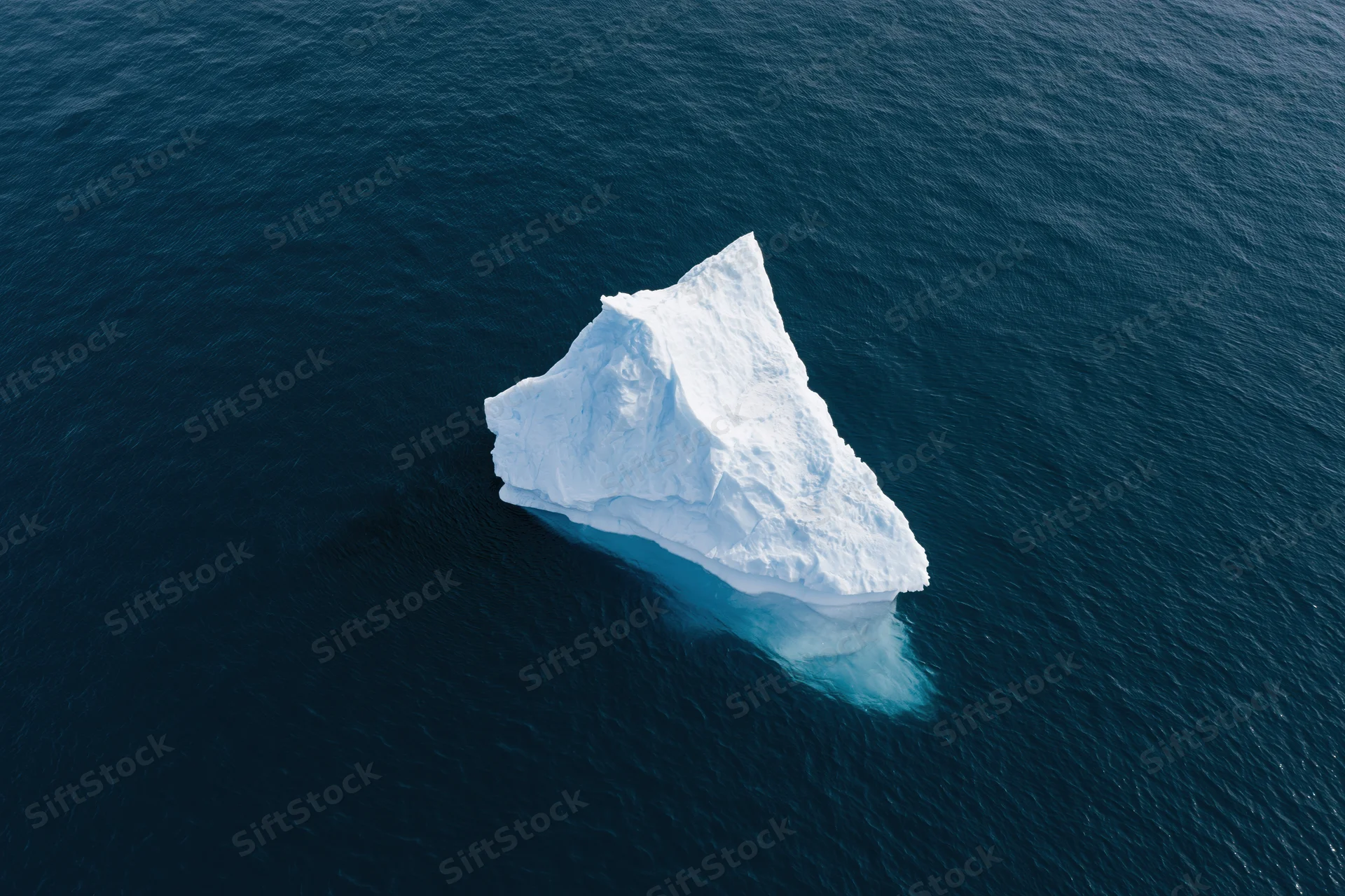 Aerial top-down view of a lone iceberg floating in deep polar ocean