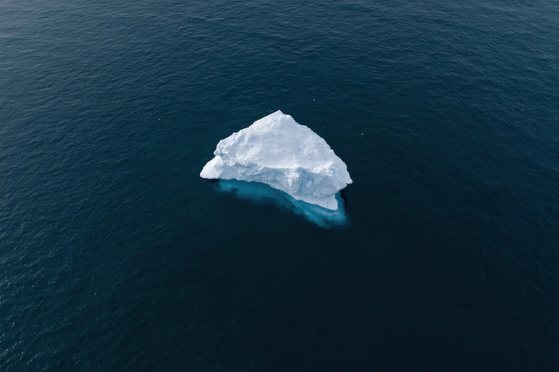 Aerial top-down view of a lone iceberg floating in deep polar ocean