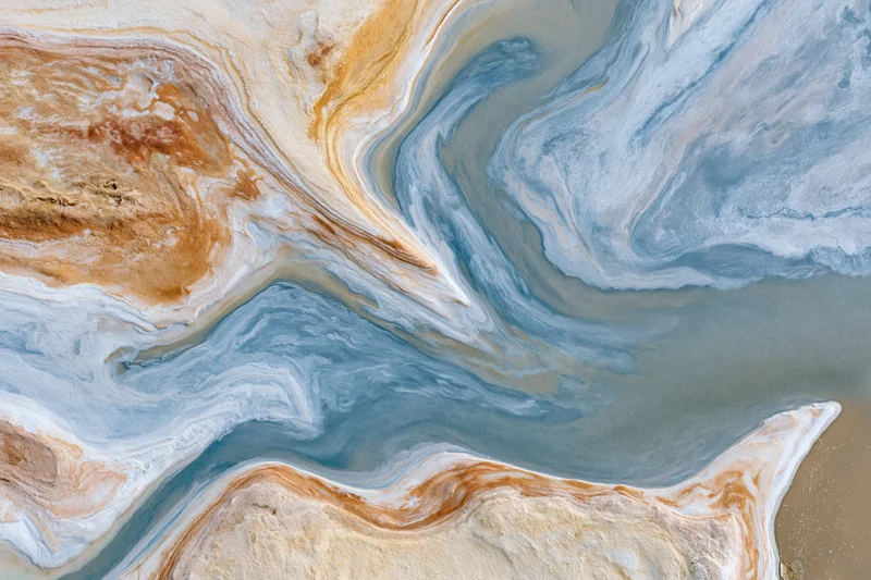 Aerial top-down view of a salt lake tidal flat landscape with swirling mineral deposits and sediment patterns