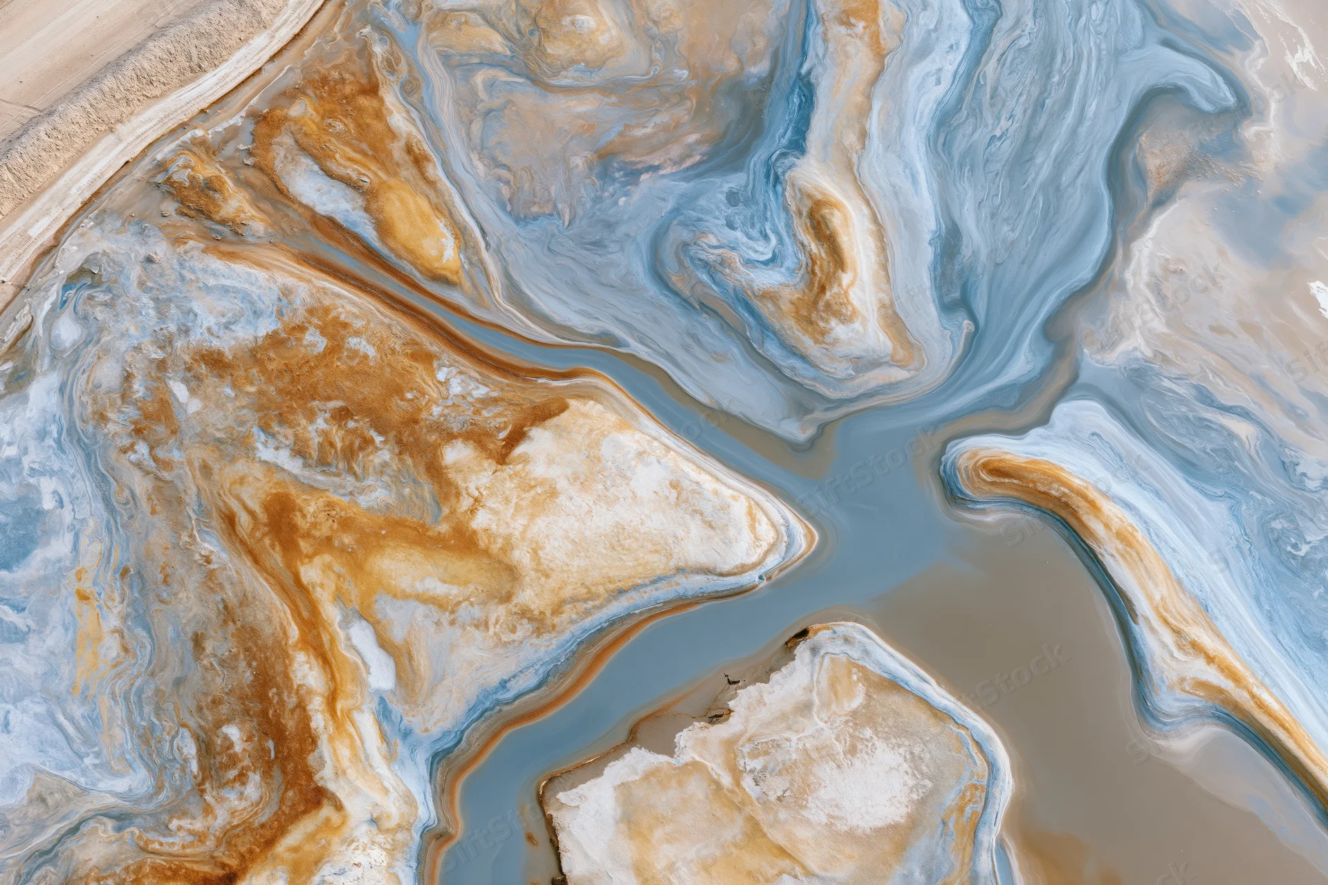 Aerial top-down view of a salt lake landscape with swirling mineral patterns and water channels