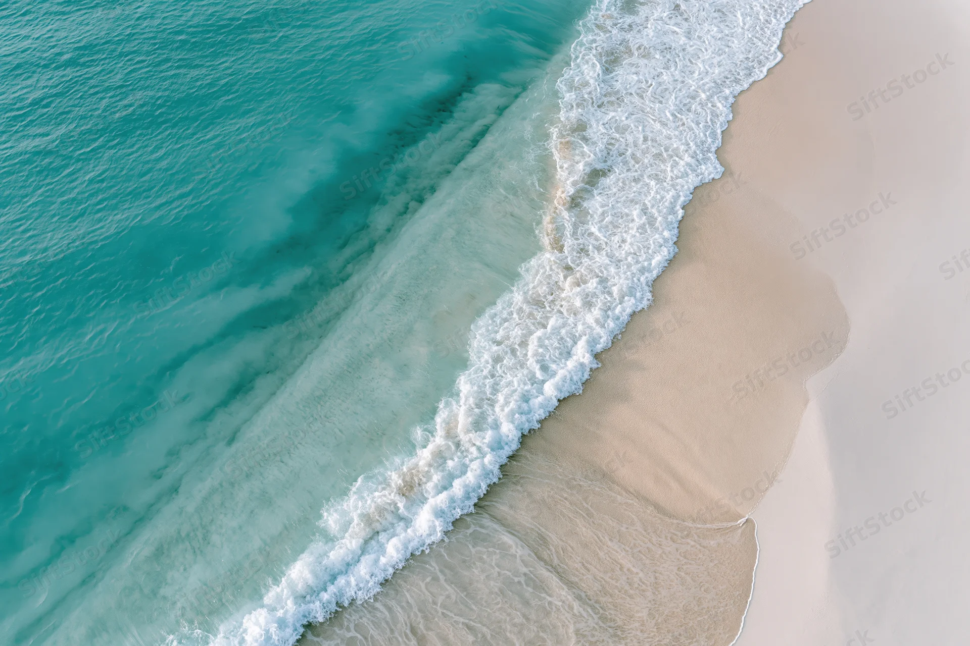 Aerial top-down view of turquoise ocean waves meeting sandy beach