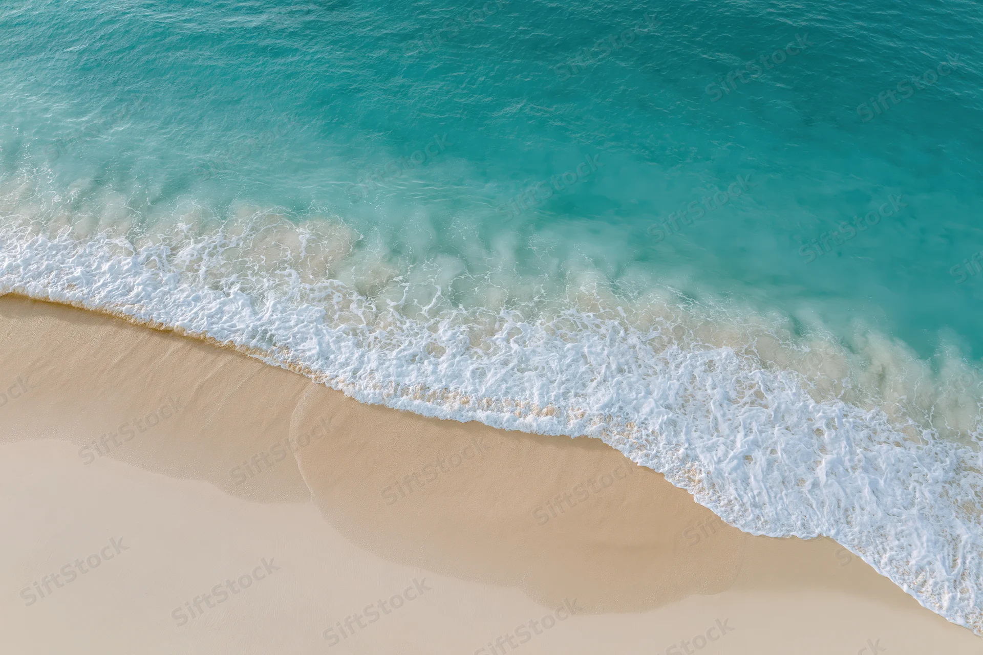 Aerial top-down view of turquoise ocean waves meeting sandy beach